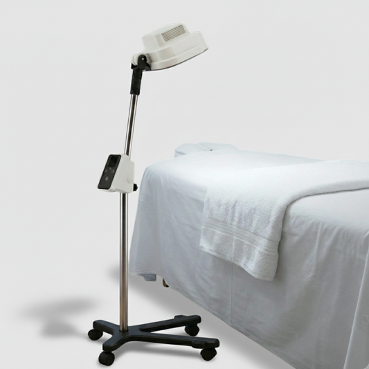 Medical lamp on a stand next to a bed with white sheets